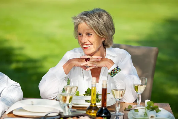 Vrouw met handen geklemd weg kijken naar eettafel — Stockfoto