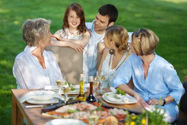 Счастливая бабушка с семьей сидя на открытом воздухе — стоковое фото