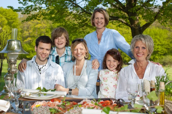 Familie lächelt gemeinsam am Esstisch — Stockfoto