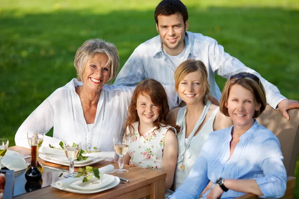 Multi generatie familie lachend samen aan eettafel — Stockfoto