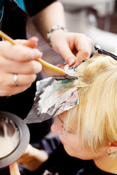 Hairdresser applying color at womans hair — Stock Photo, Image