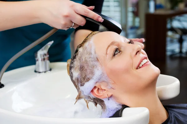 Lächelnde Frau lässt sich im Salon die Haare waschen — Stockfoto