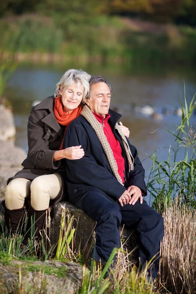 Felice coppia anziana godendo vicino a un lago — Foto Stock