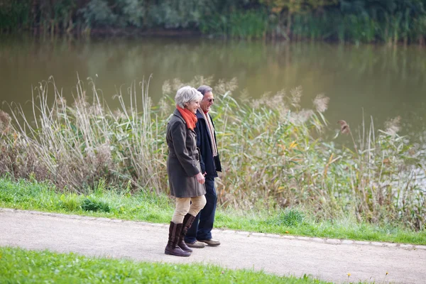 Senior couple walking alongside a lake — Stock Photo, Image