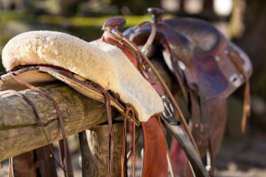 Close-up of a horse saddle on top of a fence clipart