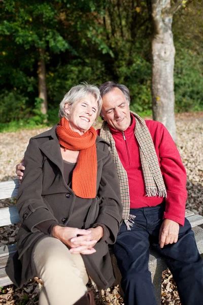 Gelukkige inschrijving senior paar zittend op een bankje — Stockfoto