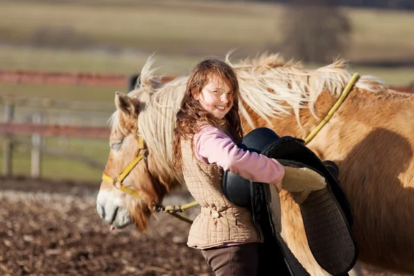 Close-up of a young girl carrying saddle — Stock Photo, Image