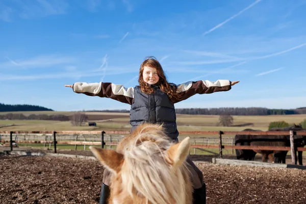 Happy girl playing on top of her horse — Stock Photo, Image