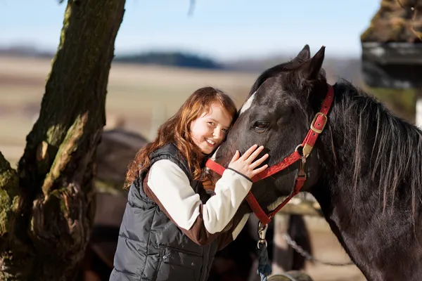Sorridente ragazza con un cavallo baia scura — Foto Stock