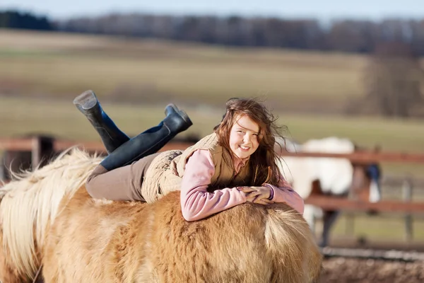 Playful young girl laying relaxed in her horse — Stock Photo, Image