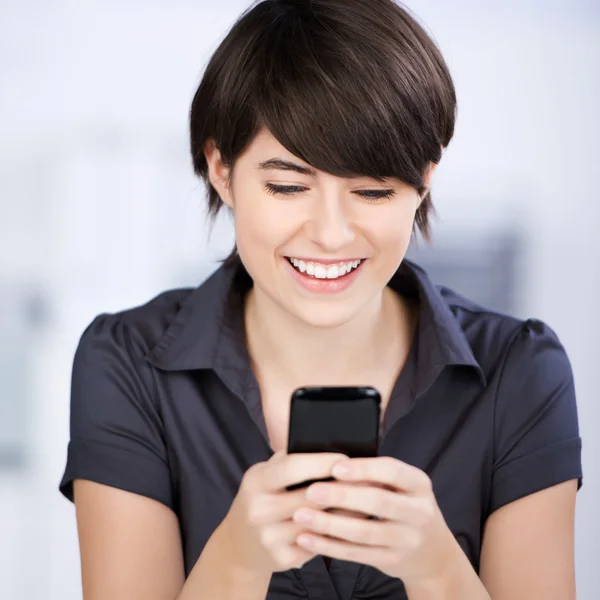 Lachende vrouw texting op haar mobiele telefoon — Stockfoto