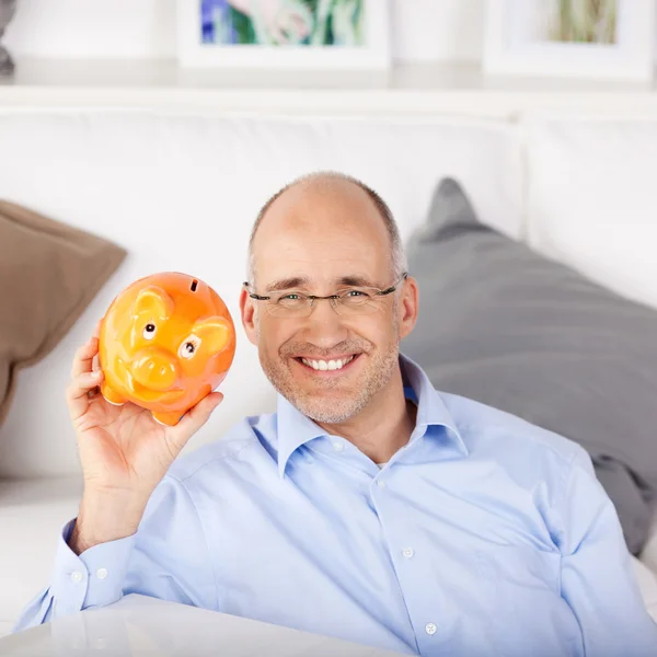 Smiling man with orange piggy bank — Stock Photo, Image