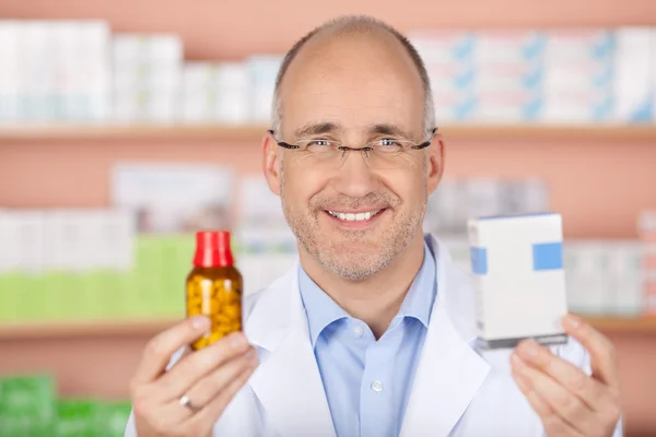 Happy pharmacist showing medicines — Stock Photo, Image
