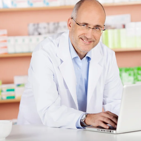 Vrolijke apotheker met laptop — Stockfoto