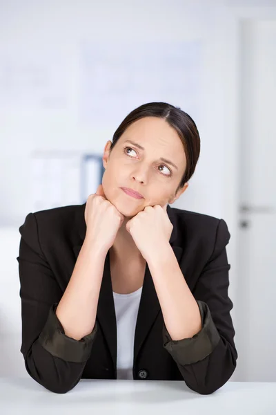 Mujer de negocios mirando hacia otro lado mientras se apoya en el escritorio —  Fotos de Stock