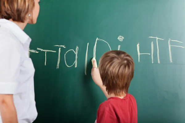 Jonge jongen schrijven op het bord — Stockfoto