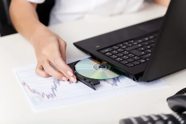 Vrouw invoegen van een cd in haar laptop — Stockfoto