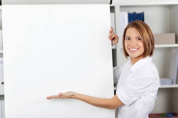 Mulher sorridente apontando para um flipchart — Fotografia de Stock