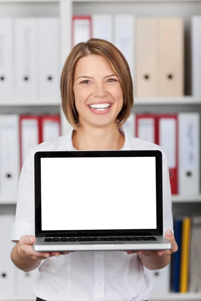 Mujer sonriente sosteniendo un portátil en blanco — Foto de Stock