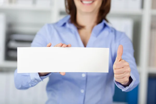 Gelukkig zakenvrouw blanco papier terwijl gebaren duimen omhoog houden — Stockfoto