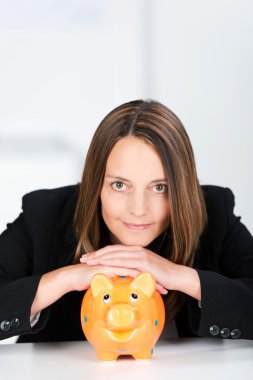 Serious Businesswoman With Piggy Bank At Desk clipart