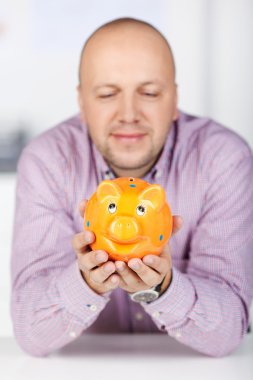 Businessman Holding Piggybank In Office clipart
