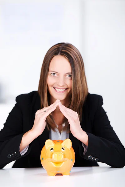 Empresária unindo os dedos acima Piggybank na mesa — Fotografia de Stock