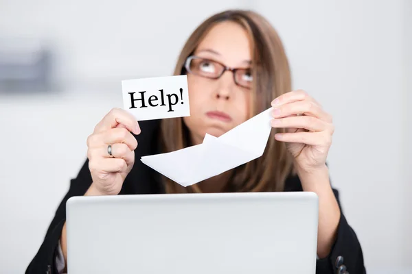 Affärskvinna med laptop med paperboat och hjälp skylt — Stockfoto