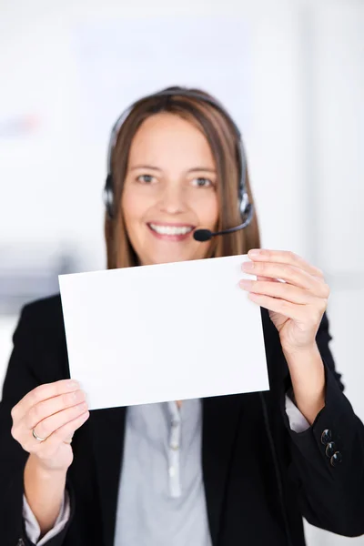 Mujer de negocios con auriculares mientras sostiene papel en blanco en Offic — Foto de Stock