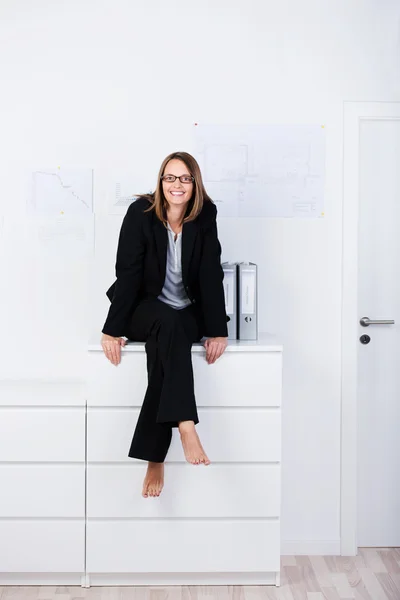 Glückliche Geschäftsfrau sitzt am Schalter im Büro — Stockfoto