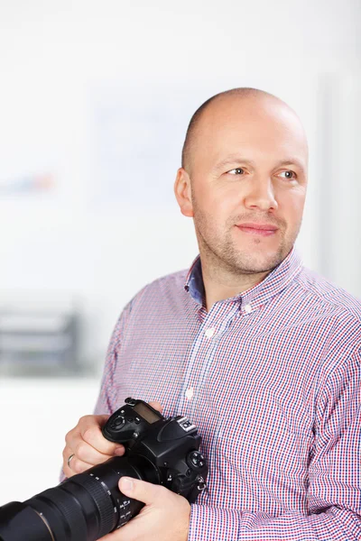 Üzletember holding tükörreflexes fényképezőgép-hivatalban — Stock Fotó