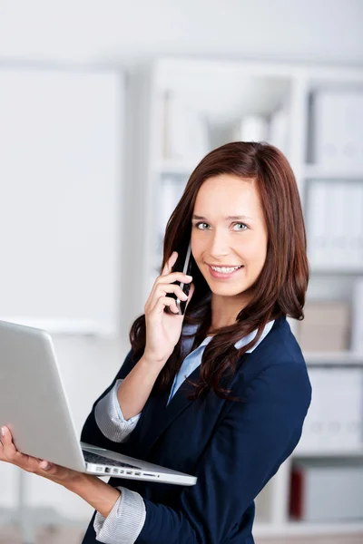 Mulher sorridente com um laptop e celular — Fotografia de Stock