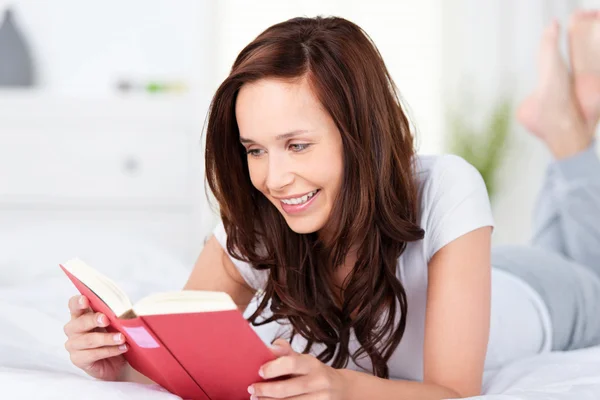 Νεαρή γυναίκα χαλάρωση και διαβάζοντας ένα βιβλίο — Φωτογραφία Αρχείου