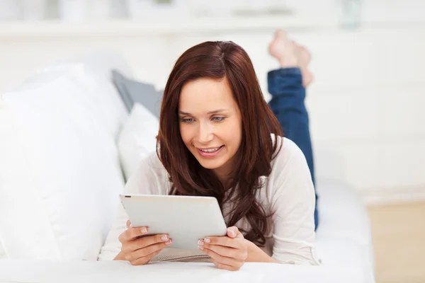 Femme relaxante sur un canapé avec une tablette — Photo