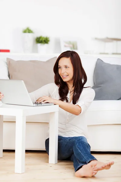 Женщина сидит на полу со своим ноутбуком — стоковое фото