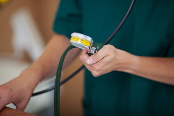 Enfermeira medir a pressão arterial enquanto segura o medidor — Fotografia de Stock