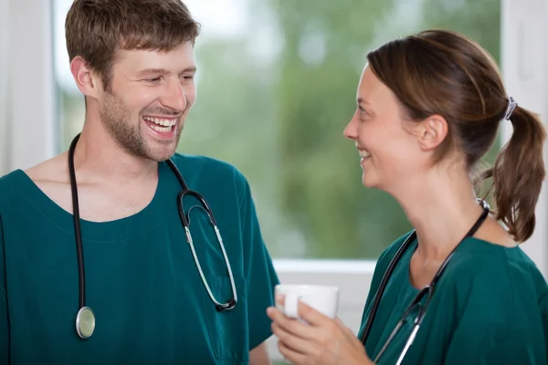 Chirurg koffiemok houden terwijl kijken naar collega — Stockfoto