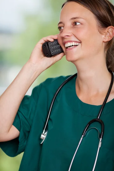 Lachende vrouw chirurg met behulp van telefoon — Stockfoto