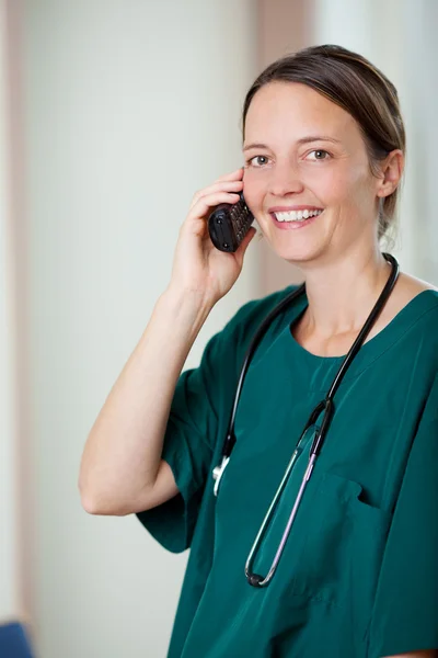 Gelukkig vrouwelijke chirurg met behulp van mobiele telefoon — Stockfoto