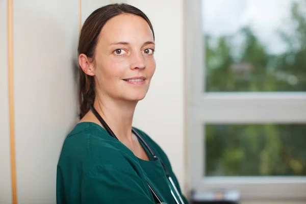 Smiling Female Surgeon Leaning On Wall At Clinic — Stock Photo, Image