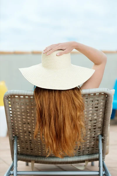 Rothaarige Frau mit Strohhut auf Liegestuhl — Stockfoto