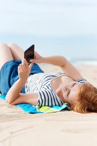 Avslappnad kvinna med cellphone på stranden — Stockfoto