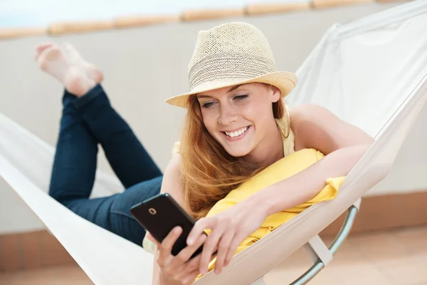 Donna sorridente con il telefono cellulare in amaca — Foto Stock