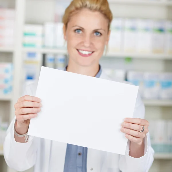 Farmacéutica femenina que sostiene papel en blanco —  Fotos de Stock