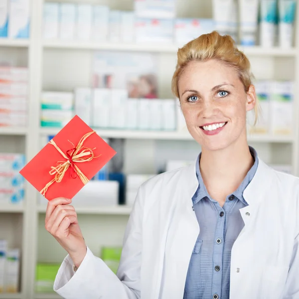 Молодая женщина-фармацевт держит подарочный купон — стоковое фото