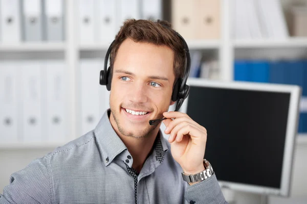 Sorridente giovane uomo con auricolare — Foto Stock