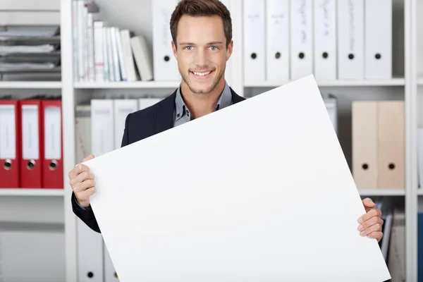 Empresario sosteniendo cartel en blanco en la oficina —  Fotos de Stock