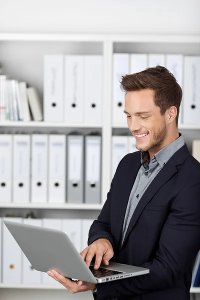 Empresário sorridente usando laptop no escritório — Fotografia de Stock