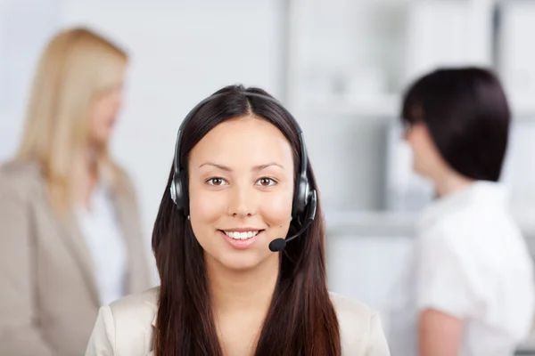Representante de atendimento ao cliente do sexo feminino usando fone de ouvido no escritório — Fotografia de Stock