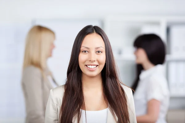 Zakenvrouw lachend met vrouwelijke collega's in de achtergrond — Stockfoto